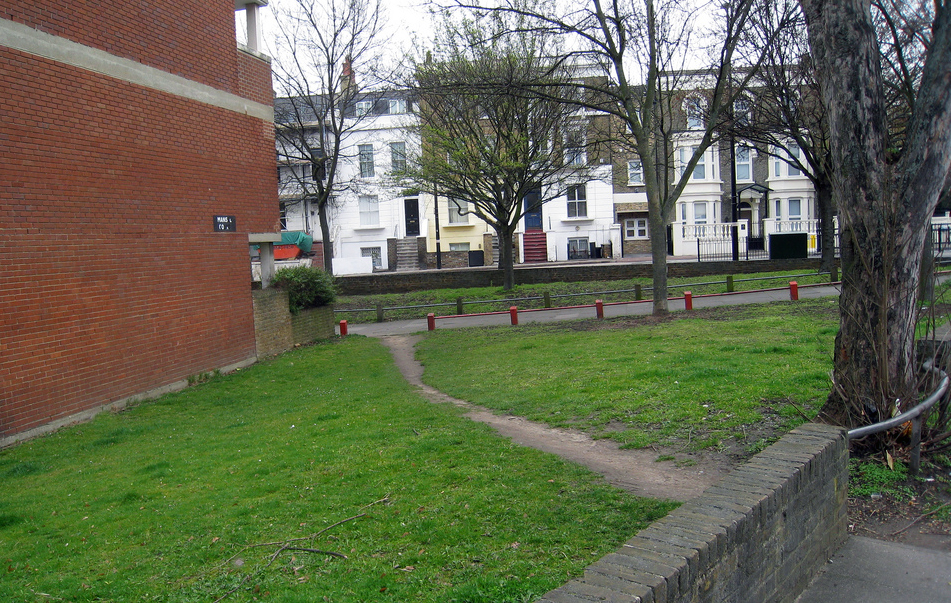 color photo of a footpath carved into a lawn from a sidewalk to the front of a brick building.