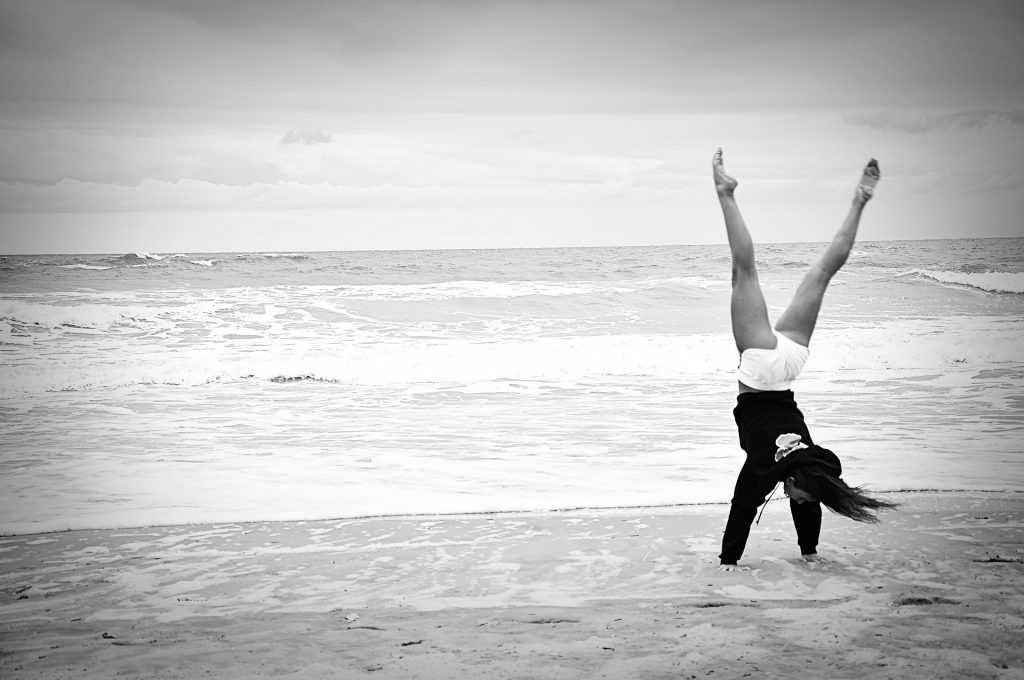 black and white photo of a person on the beach doing a handstand