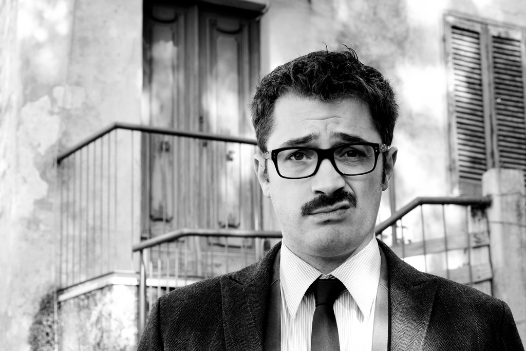 just a guy with glasses and a mustache making a grimace face